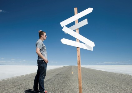 man looking at road signs on an open road